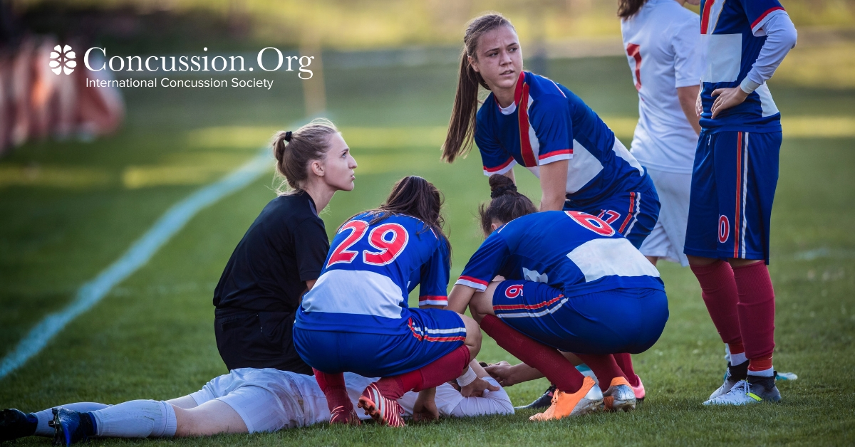 Girl soccer players huddled around an injured player